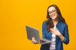 © denis_vermenko - Young happy smiling woman in casual clothes holding laptop and sending email to her best friend isolated against yellow background.