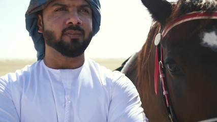 Wall Mural - Man with his horse in Dubai, walking and riding in the desert