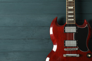 Beautiful six - string electric guitar on wooden background, space for text