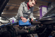 © Sergey - Man pouring oil in blue bottle in car with open hood