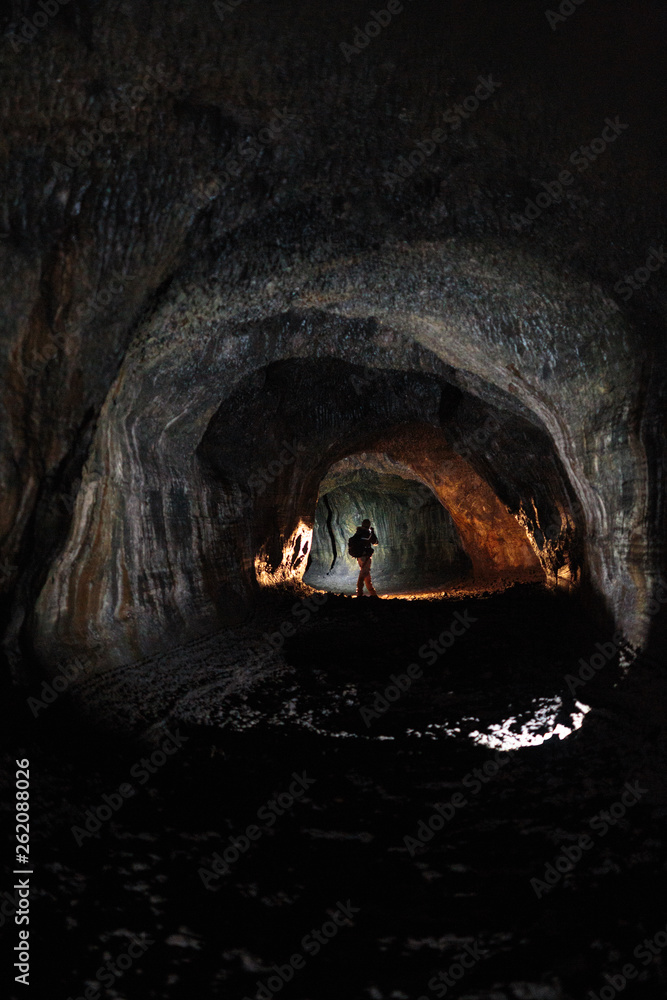 A male caver holding a propane lantern and flashlight while exploring ...