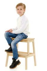 Wall Mural - A little boy is sitting on a chair.