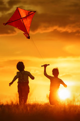 Wall Mural - Children with a kite at sunset