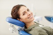 © Seventyfour - Portrait of smiling young woman lying in dental chair and looking at camera, copy space