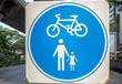 © Akara - Circle blue and white road sign on white square steel plate for pedestrian and bicycle zone mounted on metal pole