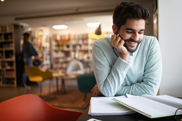 Happy student preparing exam and learning lessons in college library