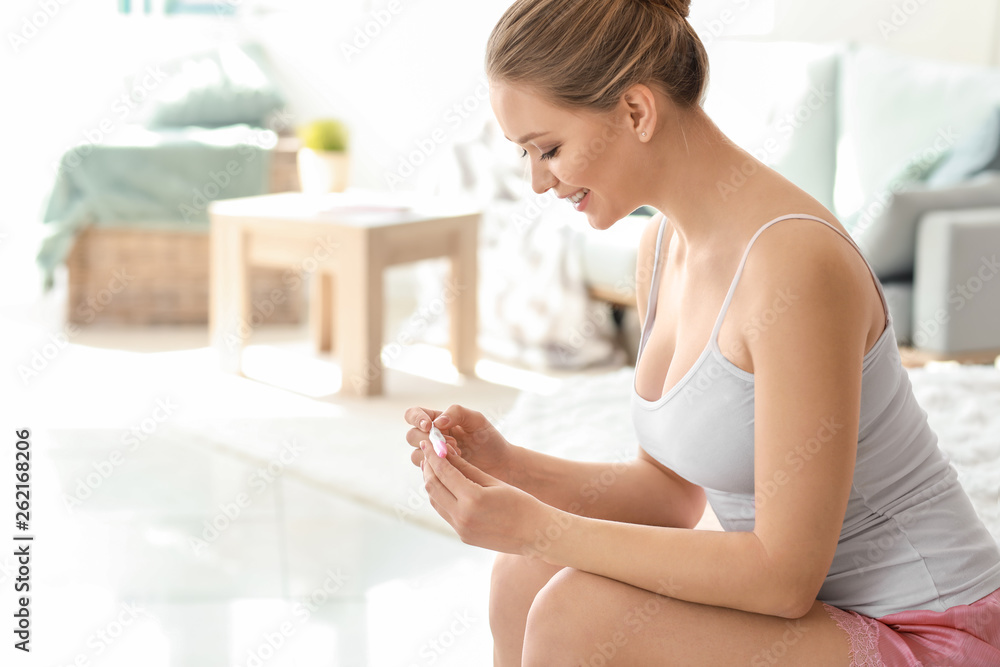 Happy young woman with pregnancy test at home