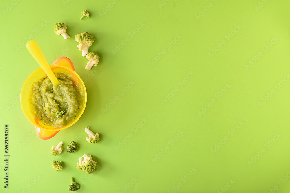 Bowl with healthy baby food on color background