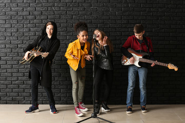 Wall Mural - Band of teenage musicians playing against dark wall