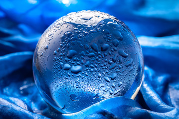Wall Mural - Crystal ball with water drops. Glass ball with drops of water in abstract blue with rays of light and reflections.