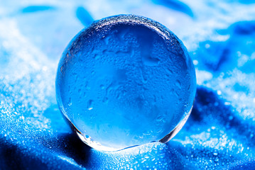 Wall Mural - Crystal ball with water drops. Glass ball with drops of water in abstract blue with rays of light and reflections.