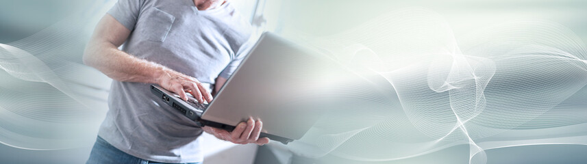 Wall Mural - Businessman standing and working on his laptop. panoramic banner