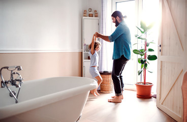 Wall Mural - Small girl with young father in bathroom at home, having fun.