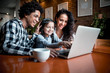 © leszekglasner - Happy multiethnic family having fun while using laptop together at restaurant