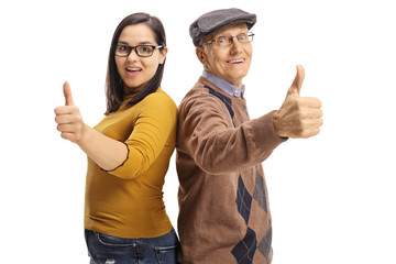 Canvas Print - Young girl and a senior man standing back to back and giving thumbs up