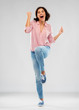 © Syda Productions - fashion, success and people concept - happy smiling young woman in striped shirt, jeans and sneakers celebrating triumph over grey background