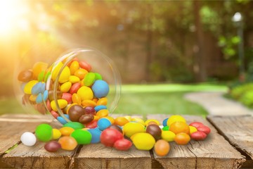 Wall Mural - Colorful candies sweets falling out of a glass jar, composition isolated over the white background