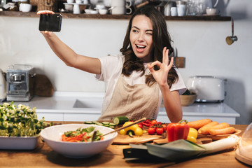 Canvas Print - Beautiful young woman wearing apron cooking vegetables