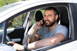 © nikodash - Man talking at mobile phone while driving a car.