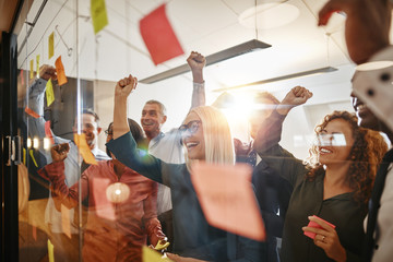 Cheering businesspeople brainstorming with sticky notes in an of