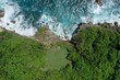 © dimabucci - Aerial view of man lying on a green cliff above the blue Indian Ocean and foaming waves, Uluwatu, Bali, Indonesia.