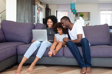 Happy African American family with daughter using laptop at home