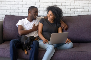 Laughing African American couple using laptop together at home