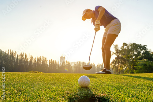 Fototapety Golf  sport-zdrowy-golfista-azjatycka-sportowa-kobieta-skupia-sie-na-kladzeniu-pilki-golfowej-na-zielonym-polu-golfowym-na-zachodzie-slonca