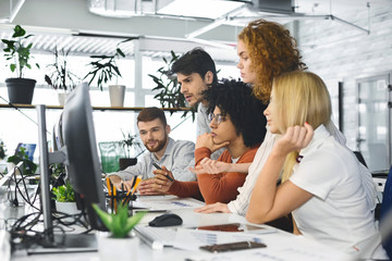 Wall Mural - Young team analyzing new information, looking at computer