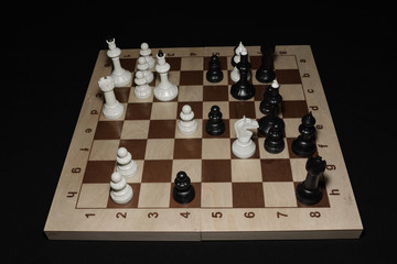 Wooden chessboard under black pieces like a strategy backdrop