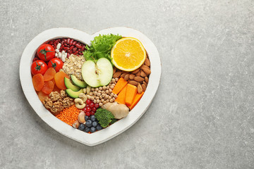 Wall Mural - Heart shaped tray with healthy products on grey background, top view. Space for text