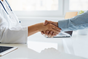 female doctor shakes hands with his patient in medical office