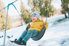 Little Boy On The Swings In Winter