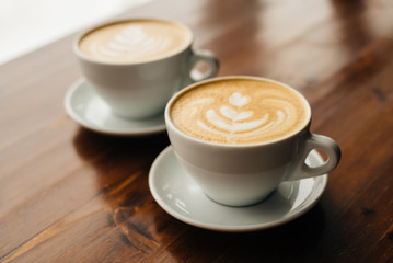 Two cups of fresh cappuccino on the wooden table.