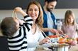 Cute little boy having fun with his young mother while eating spaghetti on kitchen at home.