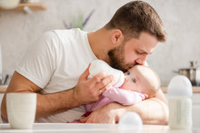 Young Father Kiss His Baby During Drinking Milk