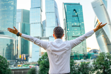 Businessman looking on copy space while standing against glass skyscraper