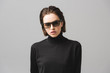 © LIGHTFIELD STUDIOS - attractive young woman in black sweater and sunglasses isolated on grey
