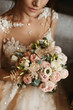 Stylish bouquet of pink and white flowers in the hands of the beautiful model girl in trendy wedding dress