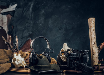 Hunters equipment and trophys on a table. Studio photo against a dark wall background