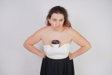 Wall Mural - chubby woman with a paper Cup of coffee stands and is disgusted with the drink, showing the emotions of the negative. plump girl hates coffee.