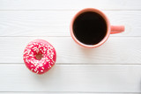Fototapeta Mapy - A cup of black coffee and sparkling pink doughnut on white wooden table baclground. Space for text, copy space. 