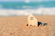 © ant - Closed up tiny home models on sand with sunlight and beach.