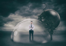 Businessman Safely Inside A Shield Dome During A Storm That Protects Him From A Wrecking Ball. Protection And Safety Concept