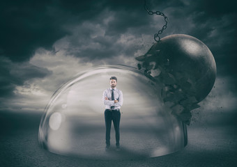 businessman safely inside a shield dome during a storm that protects him from a wrecking ball. prote