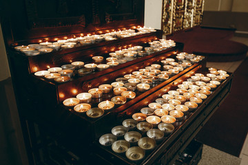 Group of burning candles on church altar close-up in christian catholic church, flaming candles, funeral, faith and memory concept