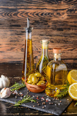 Tasty olive oil with herbs and spices on wooden table