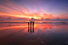 Silhouette Of Kids Standing Over The Beach With Beautiful Sunset Reflections