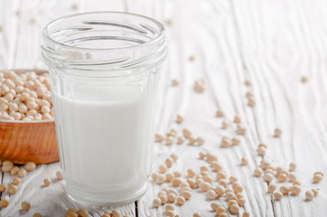 Poster - Non-dairy alternative Soy milk or yogurt in mason jar on white wooden table with soybeans in bowl aside