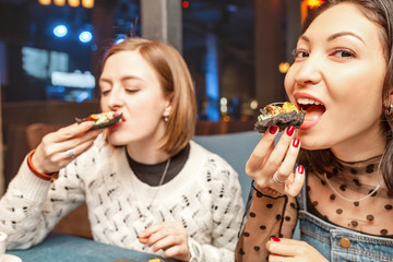 Two girlfriend girls chat and laugh in the restaurant and eat Spanish tapas. Concept of friendship and relations